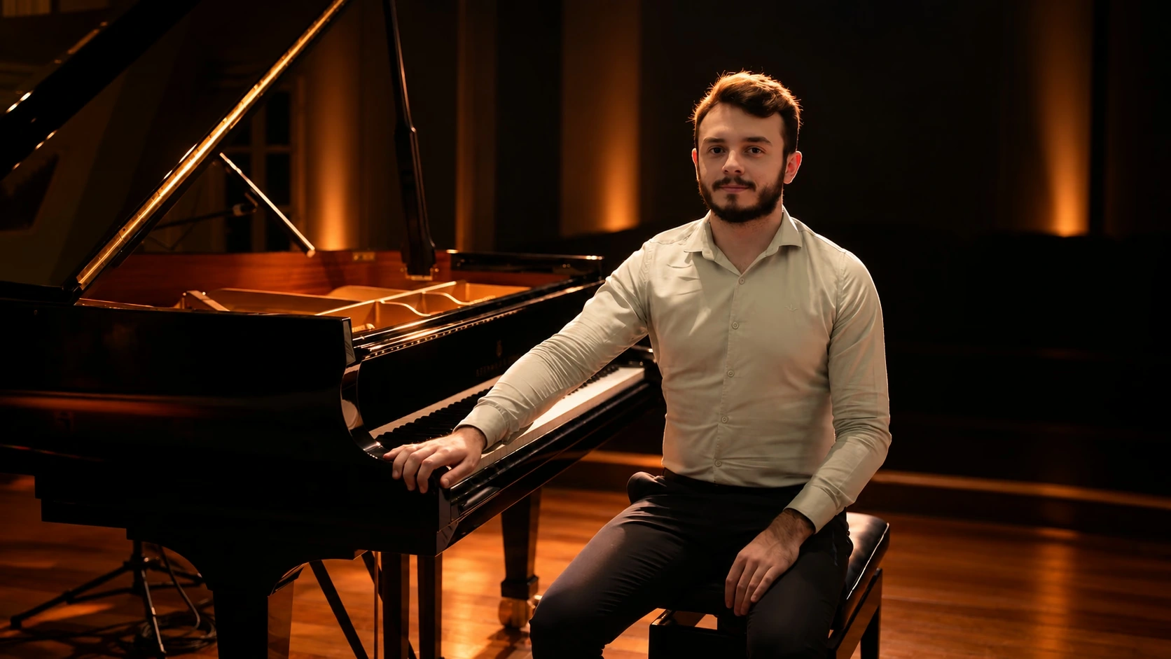 Davi Emerick sentado ao lado do piano de cauda